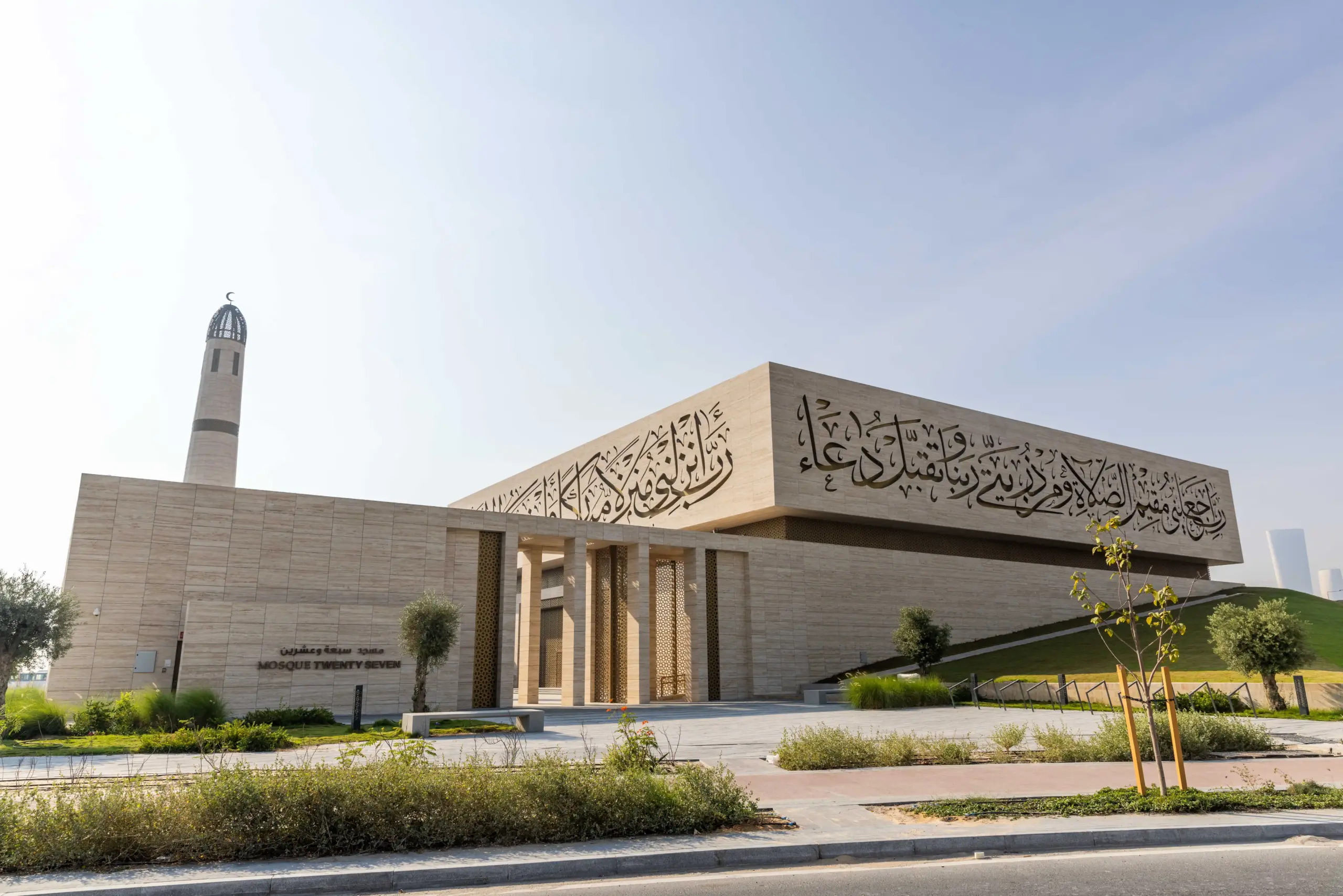 A close-up of mosque twenty seven architectural surface perforated with bright, illuminated Arabic calligraphy, suggesting a modern Islamic design feature.