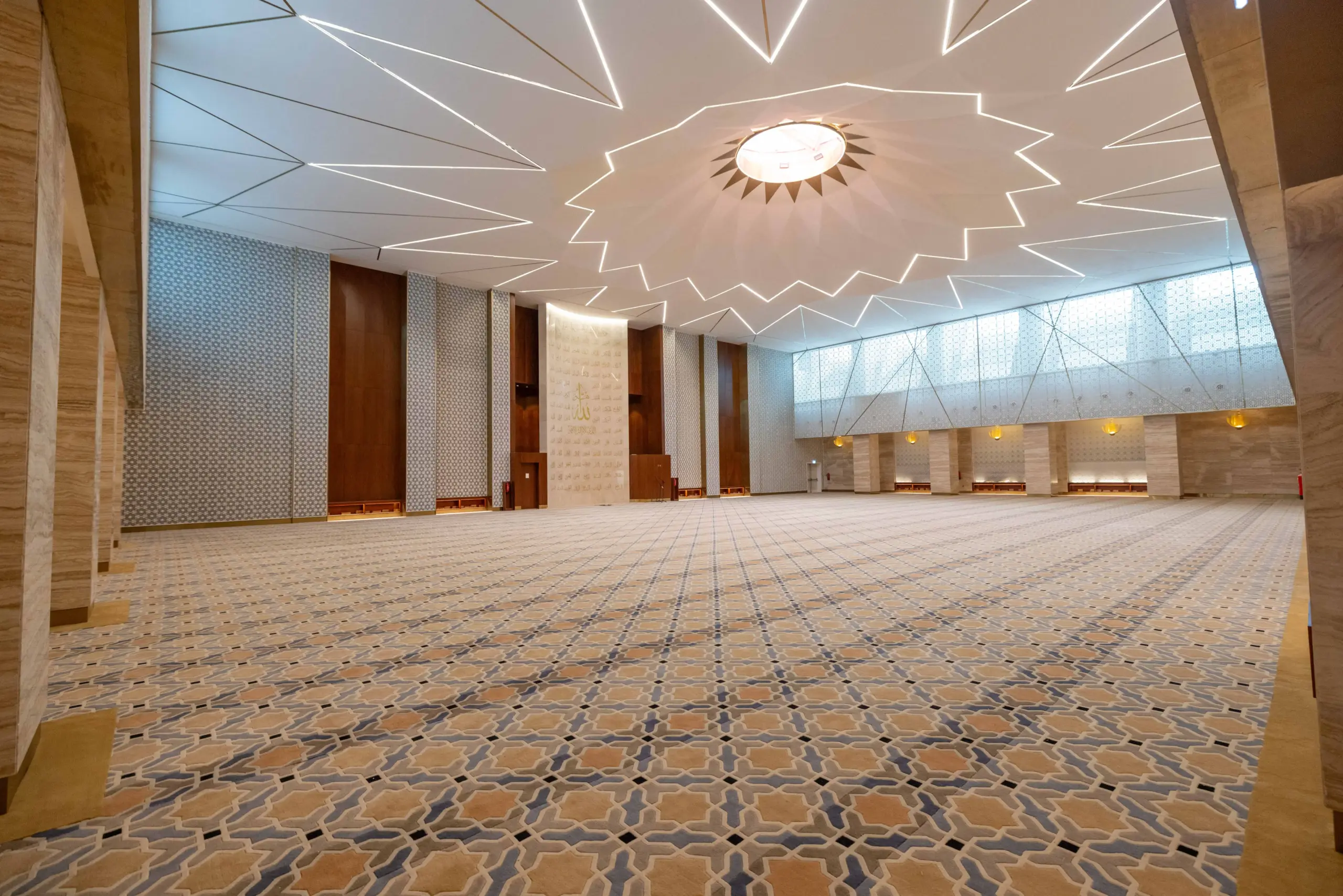 Interior hallway at Mosque Twenty-Seven with dark wood paneling, white walls, and a detailed white-and-gray Islamic geometric patterned floor
