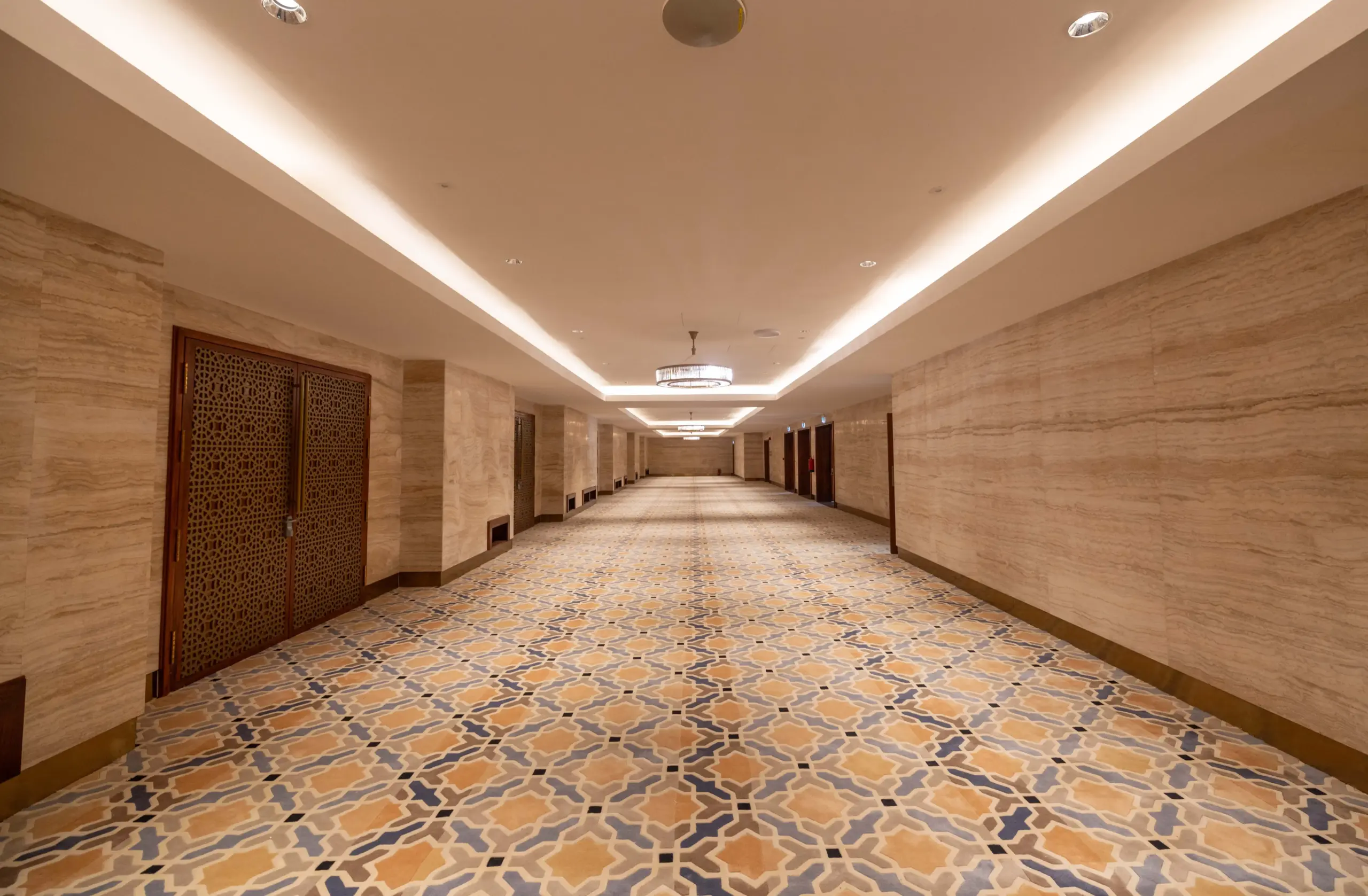 Interior hallway at Mosque Twenty-Seven with dark wood paneling, white walls, and a detailed white-and-gray Islamic geometric patterned floor