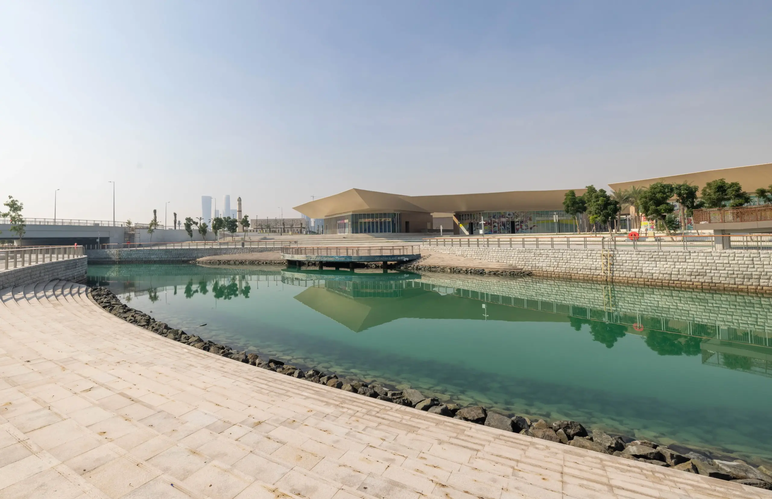 Trove East & West retail plazas on Qetaifan Island North, showing modern angular buildings along the Majra Alsail canal with outdoor dining and pedestrian promenades