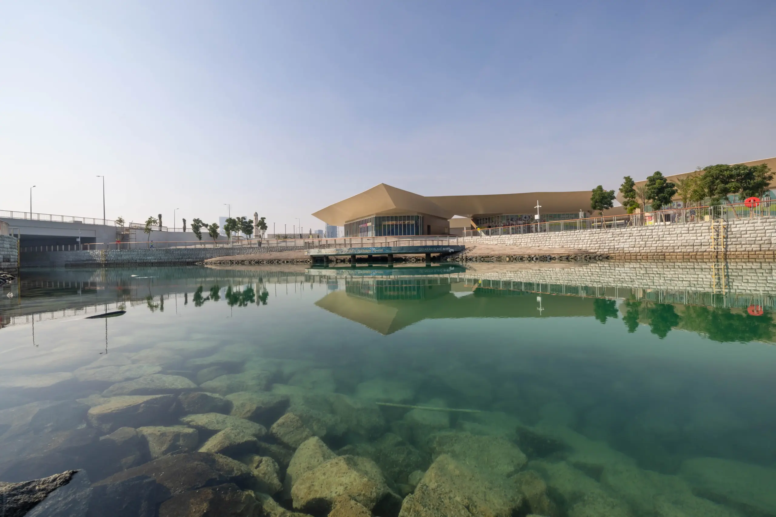 Trove East & West retail plazas on Qetaifan Island North, showing modern angular buildings along the Majra Alsail canal with outdoor dining and pedestrian promenades